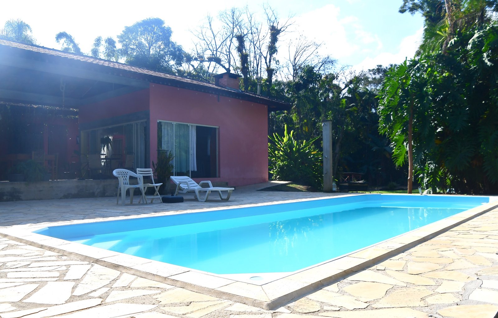 Piscina com casa e vegetação ao redor no Lote 02